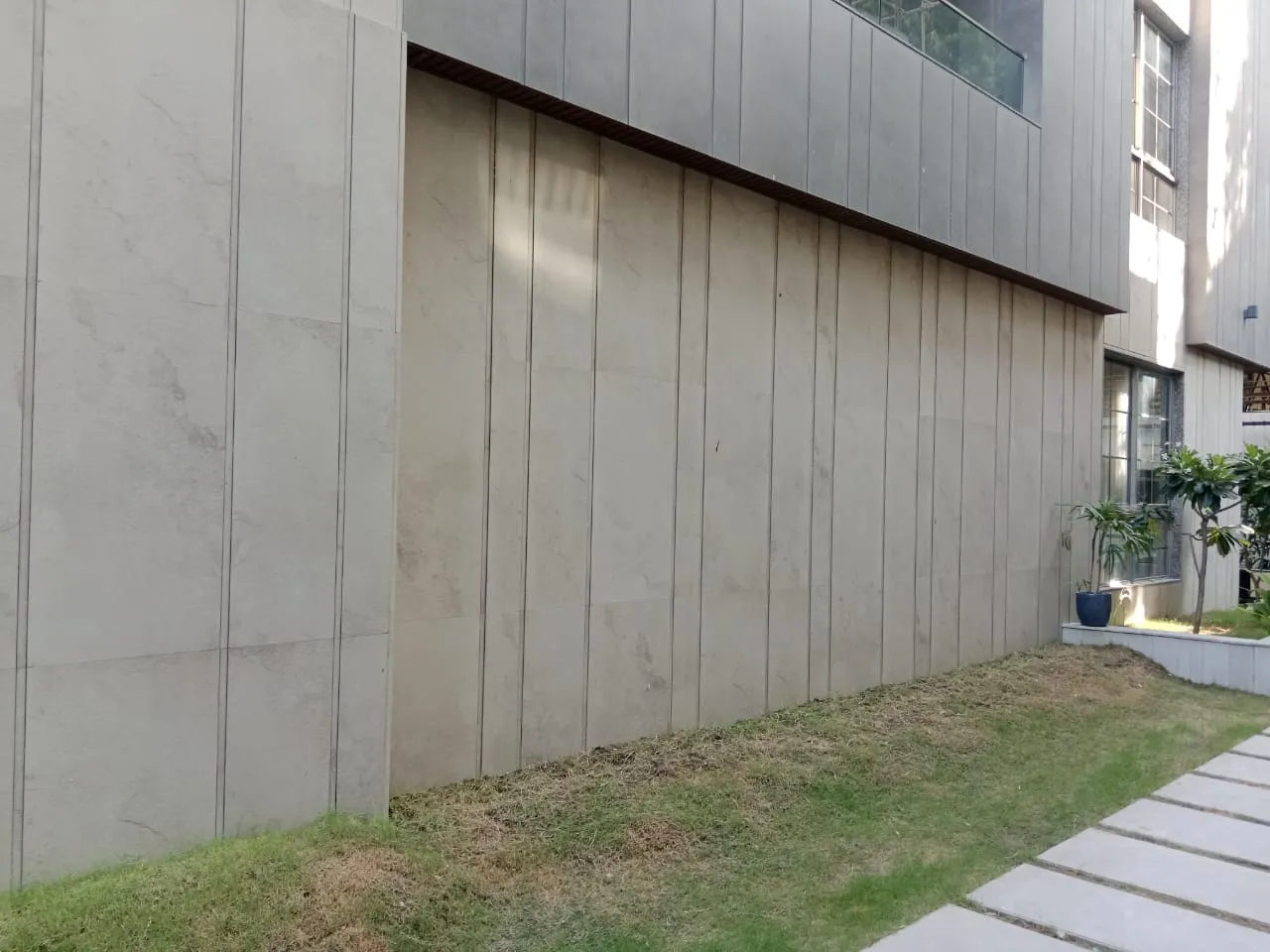 Lawn and stone stepping pavers along a clad house wall