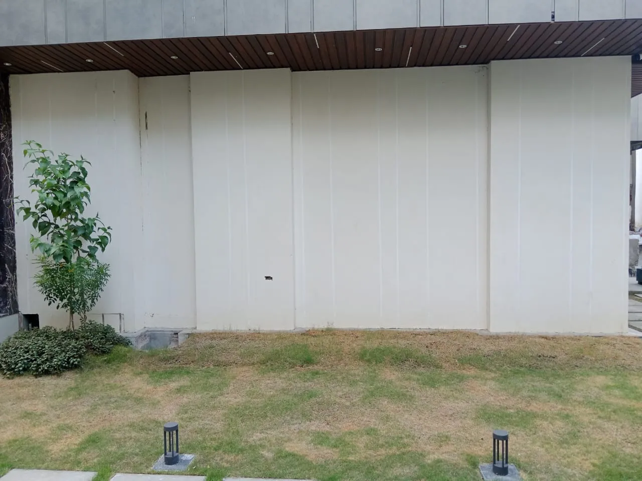 Lawn with bollard lights in front of white wall panels