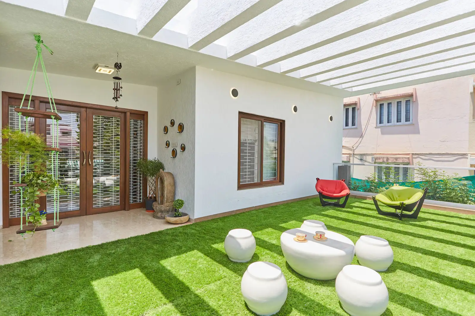 Terrace garden with artificial grass and pebble seating under a pergola