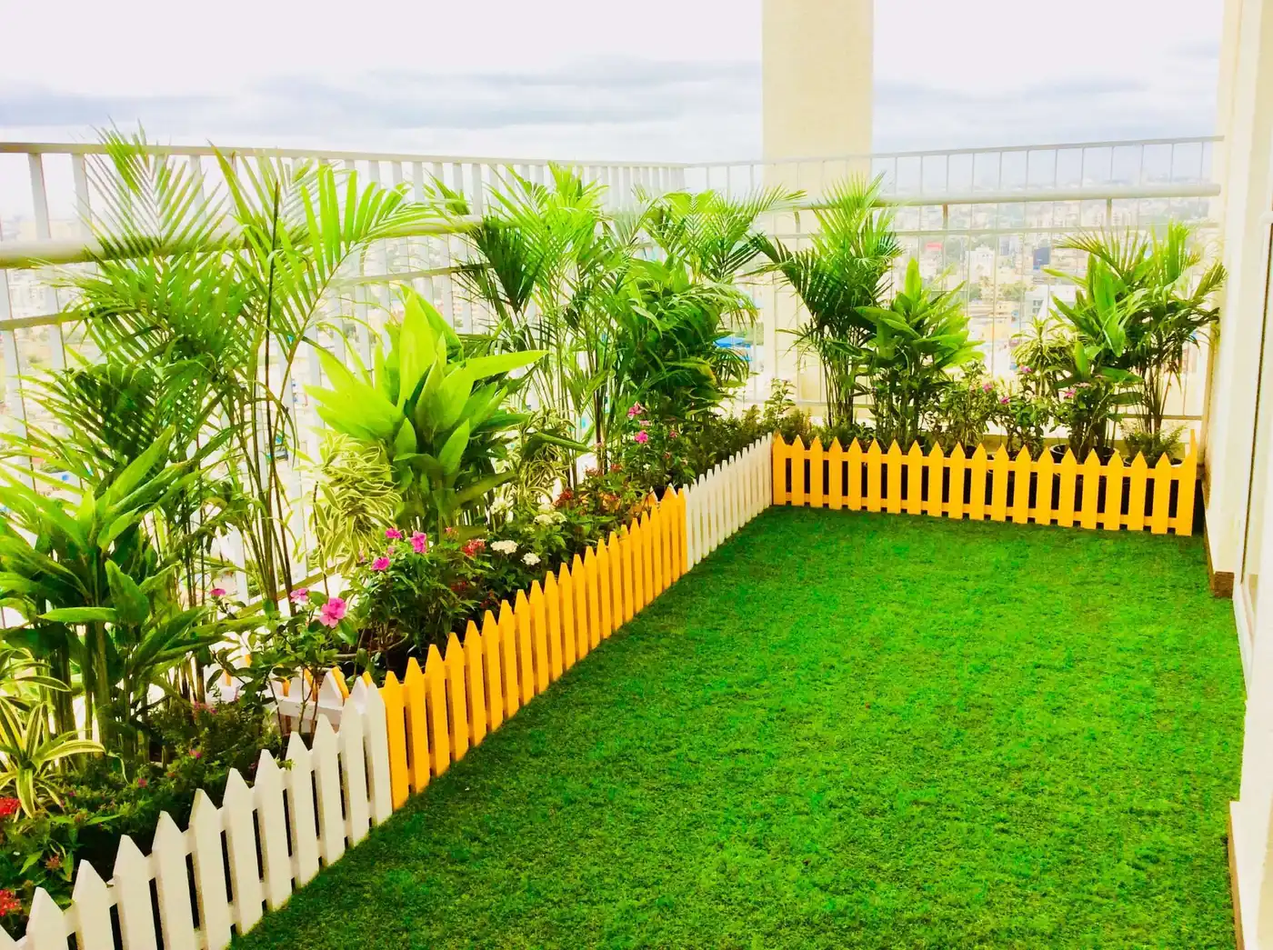 Terrace garden with lawn, palms and picket fence on a rooftop