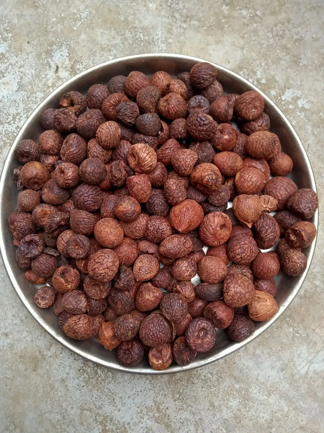Whole red dried betel nuts (supari) farm produce on a steel plate